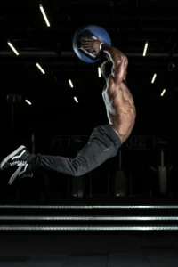 Menshealth: man jumping with exercise ball showing daily fitness habits for energy, vitality, and strength.