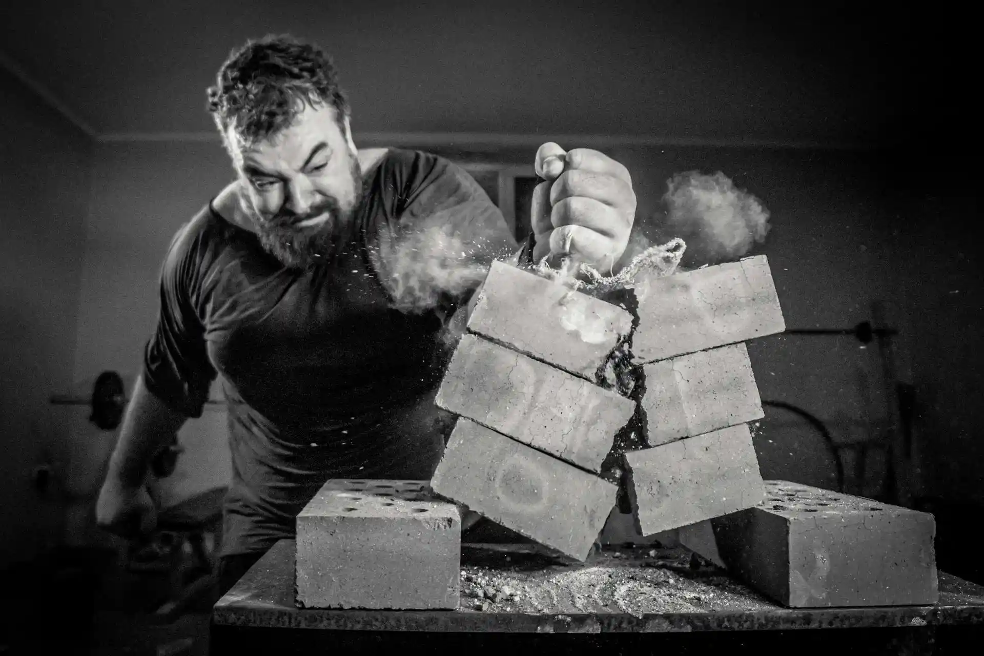 Brutal strong athlete smashing brick with fist – representing peak male energy, power, and natural testosterone boosters